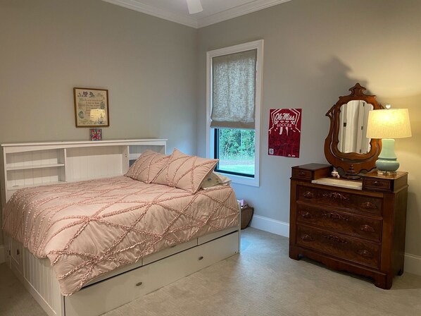 A bedroom with a bed, dresser, window, and wall decorations.
