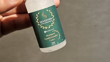 Una mano sosteniendo un pequeño frasco de acondicionador champú Silverton Paiva Experience.