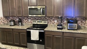 A kitchen with dark wood cabinets, a stainless steel microwave, a stove, and a coffee maker.