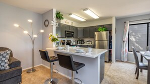 Cozinha moderna com ilha central, banquetas e área de jantar com mesa e cadeiras.