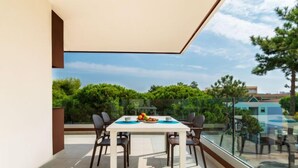 Ein moderner Essbereich mit Tisch und Stühlen, einer Glastrennwand und Blick auf Grünflächen und Gebäude.