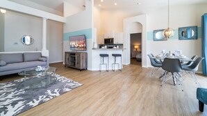 Um apartamento moderno com sala de estar, área de jantar, cozinha e uma pequena mesa de jantar com cadeiras.