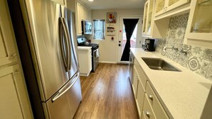 A kitchen with a stainless steel refrigerator, a stove, and a sink. -  Cozy Historic Farmhouse-2 Bedroom Downstairs Unit - Walk Downtown & Whiskey Row (Prescott)