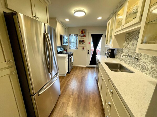 A kitchen with a stainless steel refrigerator, a stove, and a sink.