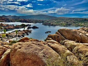 A landscape with large boulders, a body of water, and distant hills.