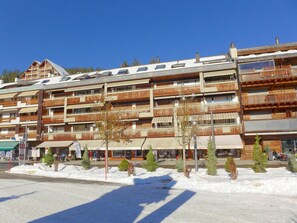 A multi-story hotel with wooden balconies and a ski resort background.