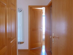 A hallway with wooden doors, a mirror, and a light fixture on the wall. - Beautiful apartment for 2 people with WIFI, TV, balcony, pets allowed and panoramic view (Crans-montana)