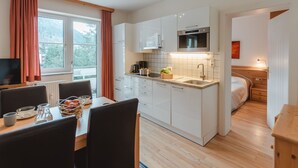 Una cucina moderna con mobili bianchi, forno integrato e una finestra con tende.