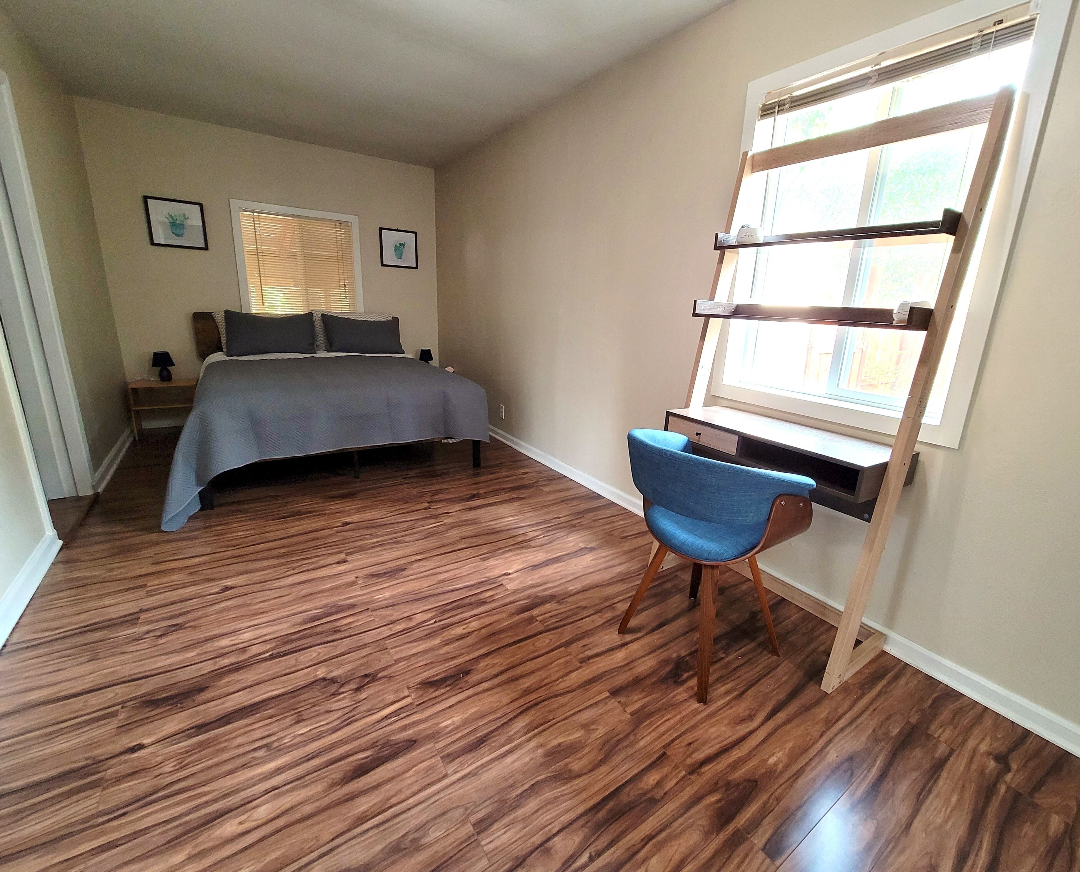 A bedroom with a bed, a desk, and a chair.