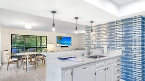 A modern kitchen with a large island, white cabinetry, and a blue patterned backsplash. - Sunset Captiva 10 - Private home just steps to the beach (Captiva)