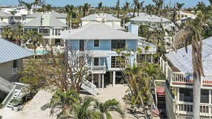 A coastal house with a prominent blue facade, multiple decks, and a sandy beach area. - Sunset Captiva 10 - Private home just steps to the beach (Captiva)