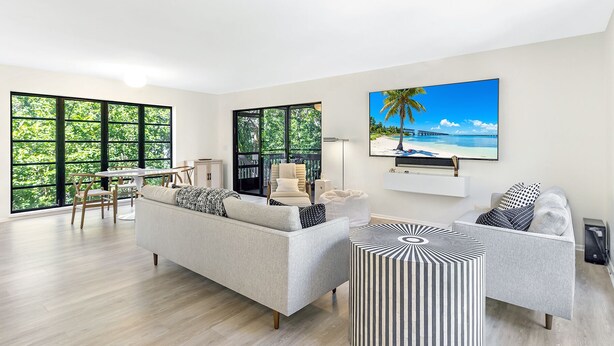 A modern living room with a grey sofa, a coffee table, and a TV mounted on the wall. - Sunset Captiva 10 - Private home just steps to the beach (Captiva)