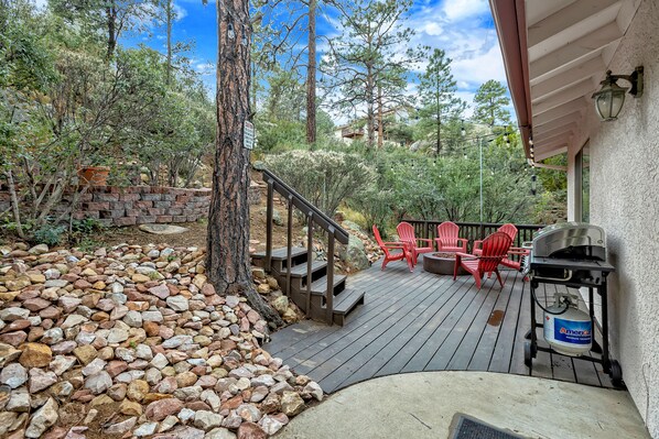 The patio is surrounded by pine trees creating a shaded and relaxing setting. - Fire Pit, Home Theater, Shuffleboard, Patio, 5-Min to Whiskey Row! (Prescott)