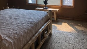 Une chambre à coucher avec un lit, un bureau, une lampe et un ventilateur de plafond.