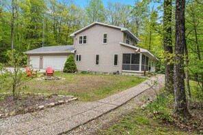 A two-story house with a garage, a covered porch, and a well-maintained lawn. - Dog-Friendly Three Little Birds Cottage on 3 Acres (Sturgeon Bay)