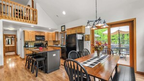 Una cocina amplia con armarios de madera, una isla central y un comedor con vistas al exterior.