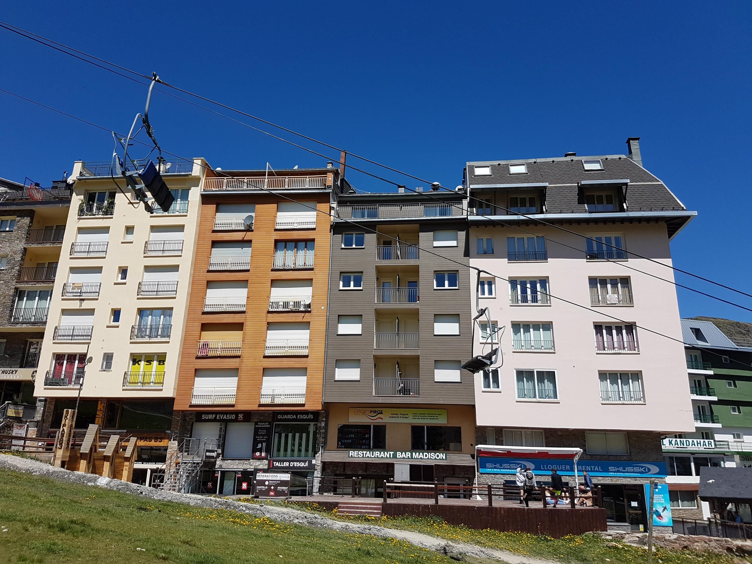 Un immeuble à plusieurs étages doté de balcons, d’un restaurant et de divers commerces.