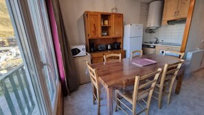 Une cuisine compacte dotée de meubles en bois, d’un réfrigérateur, d’une machine à café et d’une table à manger avec des chaises.