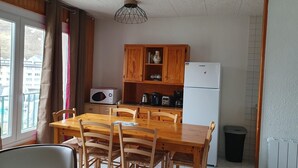 Eine kompakte Küche mit Holzausstattung, einer Mikrowelle, einem Kühlschrank und einem Esstisch mit Stühlen.