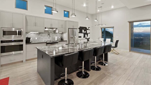 Una cocina moderna con electrodomésticos de acero inoxidable, una isla de mármol y taburetes de bar.