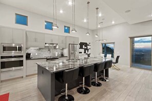 Une cuisine moderne dotée d’appareils électroménagers en acier inoxydable, d’un îlot en marbre et de tabourets de bar.