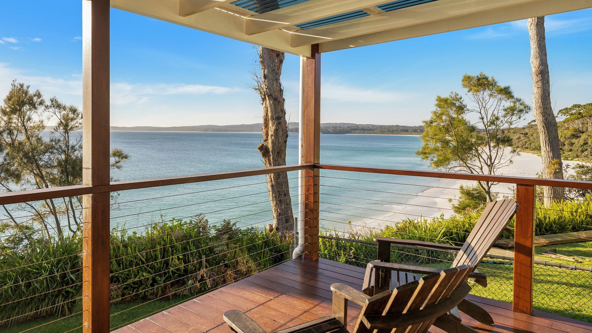 Una terraza de madera con vista a la playa y al mar.