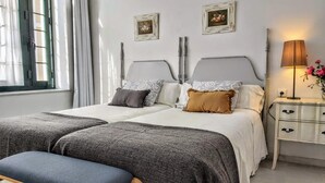 Ein Doppelbett mit zwei Kissen, ein Nachttisch mit Lampe und ein Fenster mit Vorhängen.