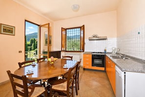 A kitchen with a dining table, chairs, a window, and a view of greenery. - Casa Andreini, Capannori, Italy (Capannori)