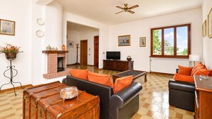 A spacious living room with a fireplace, a television, and a large window. - Casa Andreini, Capannori, Italy (Capannori)