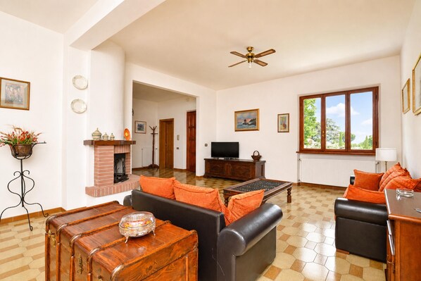 A spacious living room with a fireplace, a television, and a large window. - Casa Andreini, Capannori, Italy (Capannori)