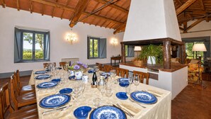 Un comedor con una larga mesa lista para una comida, sillas de madera y un techo alto con vigas a la vista.