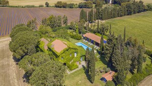 Vista aérea de una propiedad con piscina, una casa de techo rojo y campos circundantes.