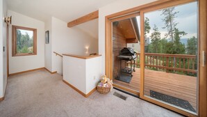 Une pièce dotée d’une terrasse en bois, d’une cheminée et offrant une vue sur l’extérieur.