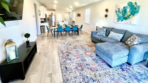 Un salon moderne avec un canapé bleu, un tapis à motifs et un coin repas avec des chaises bleues.