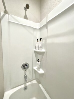 Een bad/douchecombinatie, een haardroger, handdoeken, zeep