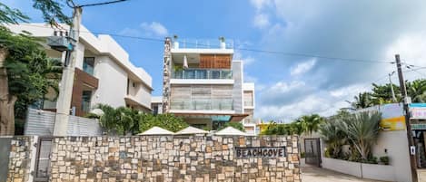 Un edificio moderno de varios pisos con un muro de piedra con la leyenda