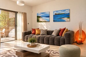 Ein modernes Wohnzimmer mit einem grauen Sofa, einem weißen Couchtisch und zwei Bildern von Küstenlandschaften.