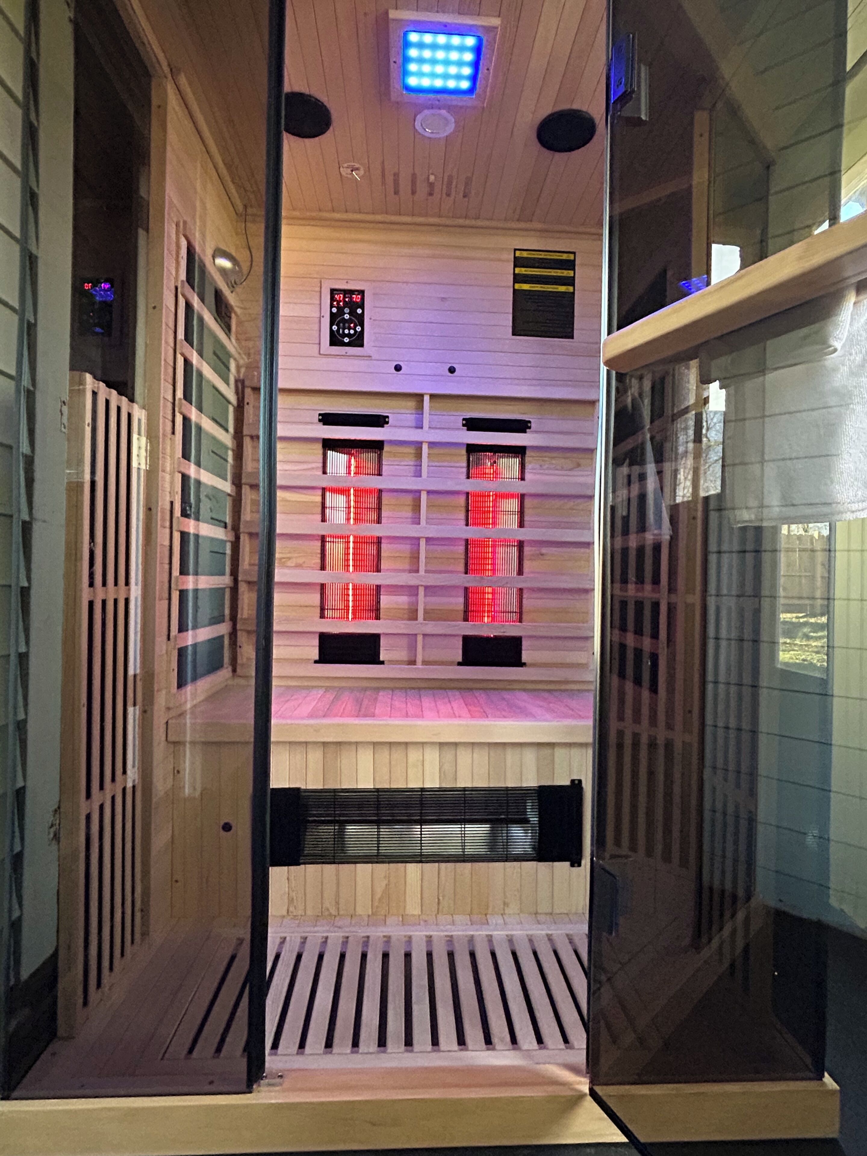 A sauna with wooden walls, a sloped ceiling, and a control panel with a digital display.