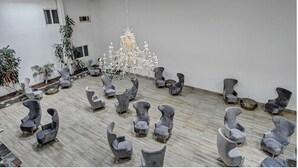 A spacious room with a modern chandelier, grey upholstered chairs arranged in a circle, and a wooden floor. - Melour Resort (Tannersville)