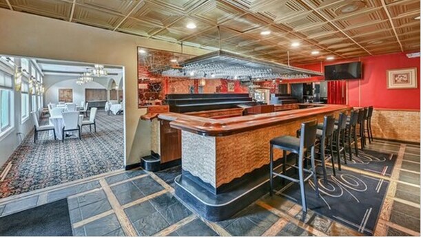 A bar area with a wooden ceiling, a counter, and bar stools. - Melour Resort (Tannersville)