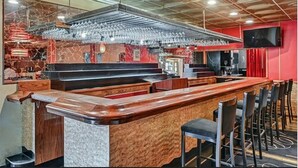 A bar area with a wooden counter, bar stools, and a hanging light fixture. - Melour Resort (Tannersville)