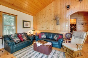 A cozy living room with a leather sofa, a wooden rocking chair, and a vintage suitcase.