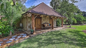 Una casa in pietra con tetto in tegole, un portico e un piccolo giardino con vialetto in pietra e piante in vaso.