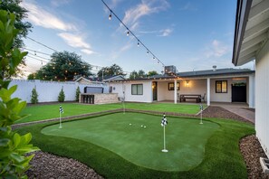 A backyard with a putting green, a patio area, and string lights. - Monterosa Green - BEST WALKABLE LOCATION in Charming Arcadia Lite w/ SPA! (Phoenix)