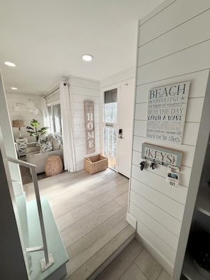 A modern interior with a staircase leading to a living area, a wall-mounted key rack, and a 'HOME' sign.