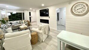 Ein modernes Wohnzimmer mit flachbildfernseher an der Wand, einer großen Uhr und einem Sofa.