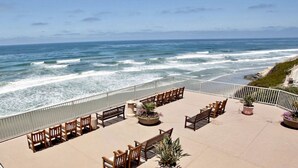 Eine Strandterrasse mit Holzmöbeln und Topfpflanzen mit Blick auf das Meer.