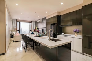 A modern kitchen with a central island, dark cabinetry, and a large window offering a city view.