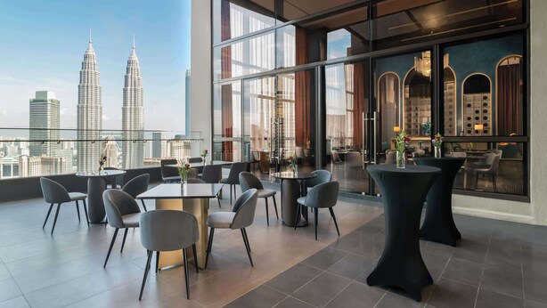 Una habitación de hotel moderna con una vista panorámica de la ciudad, destacando dos rascacielos imponentes.