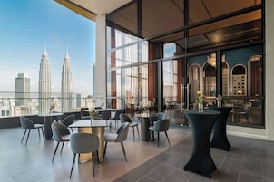 A modern hotel room with a panoramic city view, featuring two prominent skyscrapers.